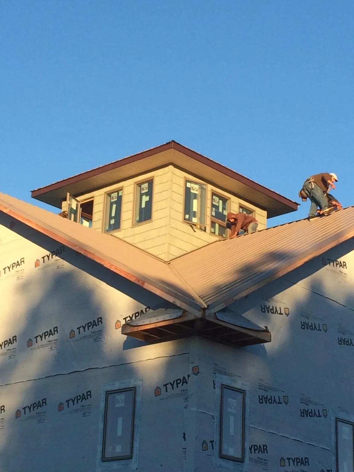 Roofers working around a rooftop cupola on a new metal roof at sunset — Roof Waterproofing in Inman by Roofing Brothers